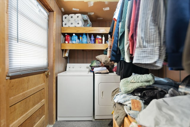 laundry area with wooden walls, carpet flooring, and washer and clothes dryer