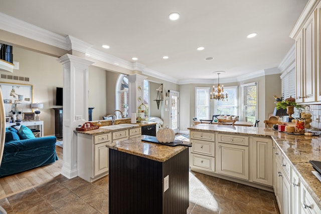 kitchen featuring crown molding, pendant lighting, kitchen peninsula, and cream cabinets