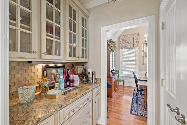 kitchen featuring ornamental molding, light hardwood / wood-style floors, backsplash, and light stone countertops