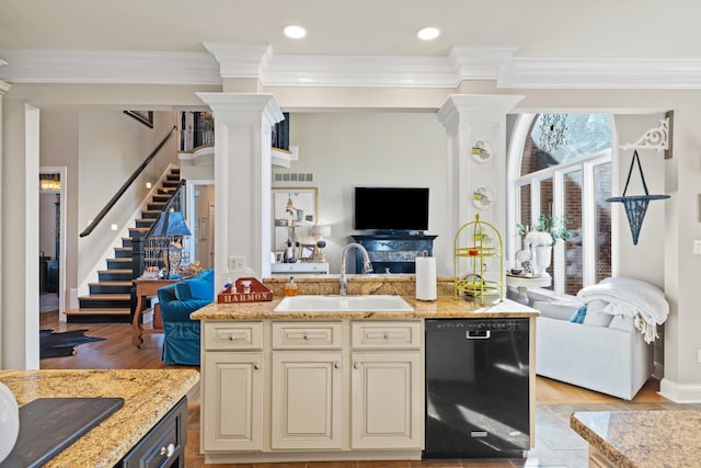 kitchen with dishwasher, cream cabinets, sink, and light stone counters