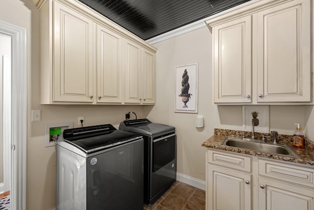 laundry room with dark tile patterned flooring, washing machine and dryer, cabinets, and sink