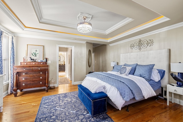 bedroom with ornamental molding, hardwood / wood-style floors, a chandelier, and a tray ceiling