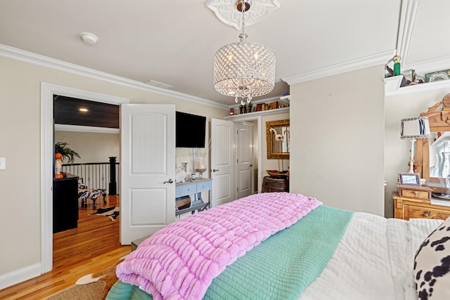 bedroom featuring a notable chandelier, ornamental molding, and light hardwood / wood-style flooring