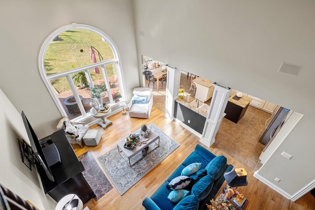 living room featuring hardwood / wood-style floors, a towering ceiling, and decorative columns