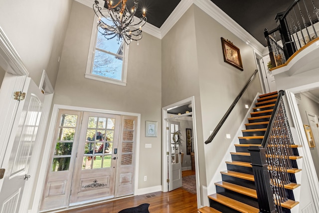 entrance foyer featuring ornamental molding, an inviting chandelier, dark hardwood / wood-style floors, and a towering ceiling