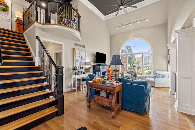 living room featuring ornamental molding, light hardwood / wood-style floors, rail lighting, and a high ceiling