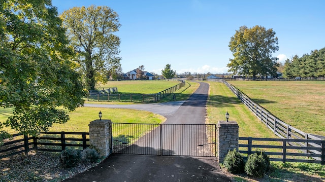 view of gate with a lawn and a rural view