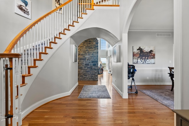 foyer featuring a towering ceiling, ornamental molding, and hardwood / wood-style flooring