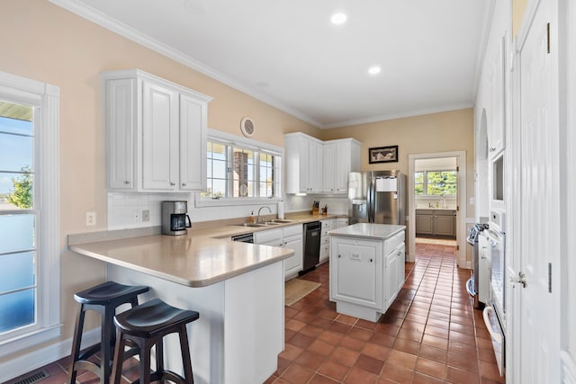 kitchen featuring appliances with stainless steel finishes, kitchen peninsula, a kitchen island, and white cabinets