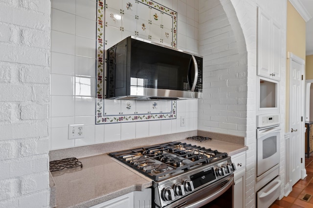 kitchen with decorative backsplash, white cabinetry, and stainless steel appliances