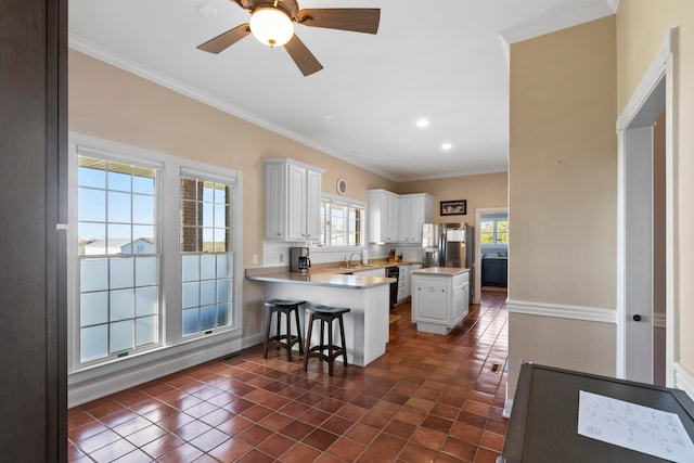 kitchen featuring a kitchen island, kitchen peninsula, ornamental molding, sink, and white cabinets