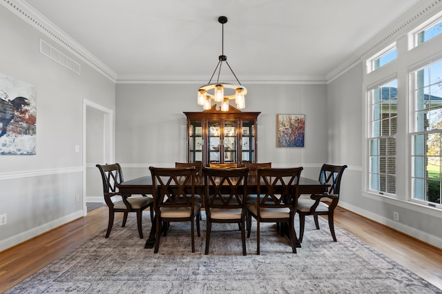 dining space featuring crown molding, hardwood / wood-style flooring, and a chandelier