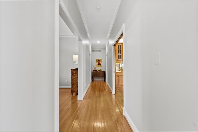 corridor with light hardwood / wood-style flooring and crown molding