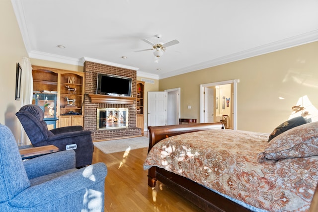 bedroom with crown molding, light hardwood / wood-style flooring, a fireplace, and ceiling fan