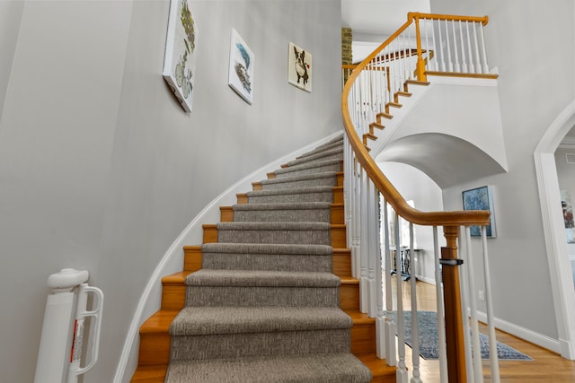 stairs featuring wood-type flooring and a towering ceiling