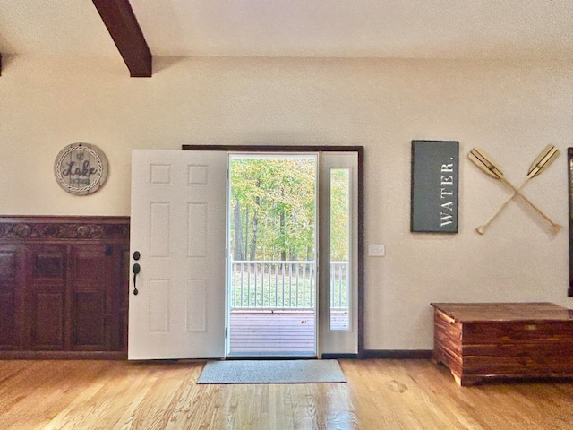 foyer entrance featuring light hardwood / wood-style floors and beam ceiling