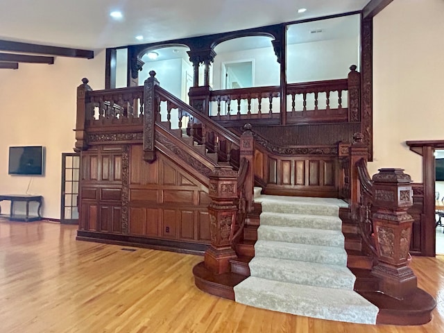 stairs featuring decorative columns and wood-type flooring