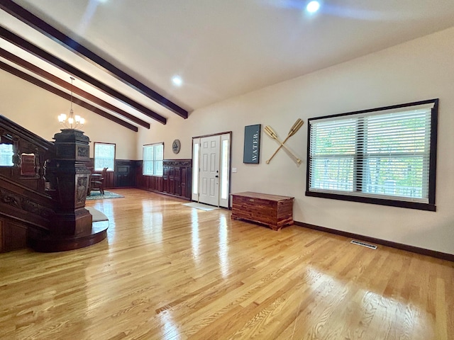 foyer entrance with lofted ceiling with beams, light hardwood / wood-style floors, and a notable chandelier