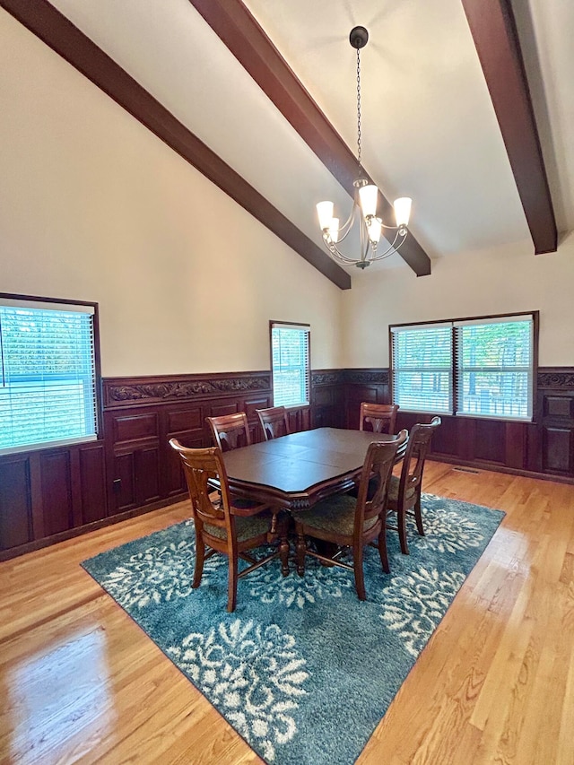 dining area with a chandelier, beam ceiling, light hardwood / wood-style flooring, and high vaulted ceiling