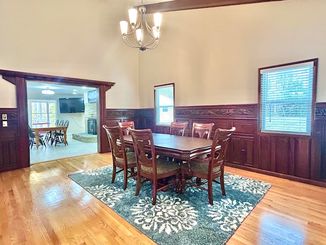 dining area with a high ceiling, light wood-type flooring, and an inviting chandelier