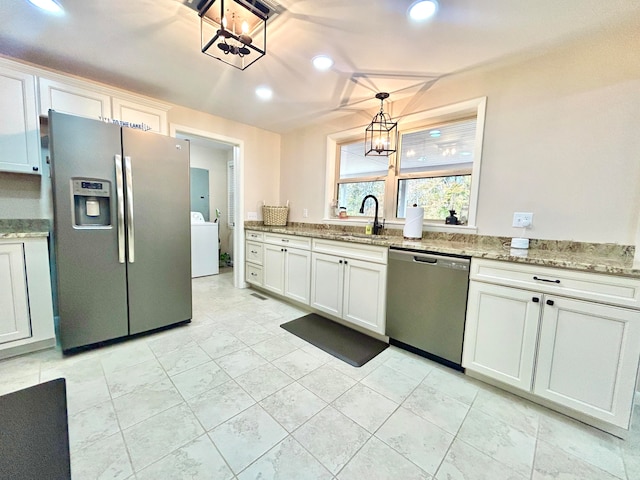 kitchen featuring stainless steel appliances, white cabinetry, sink, light stone counters, and decorative light fixtures