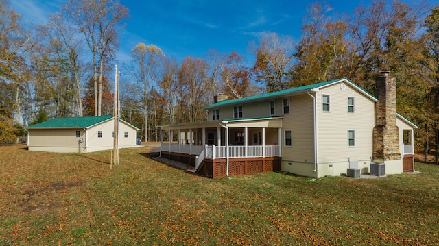 rear view of house with central AC unit and a yard