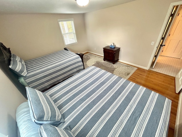 bedroom with lofted ceiling and wood-type flooring