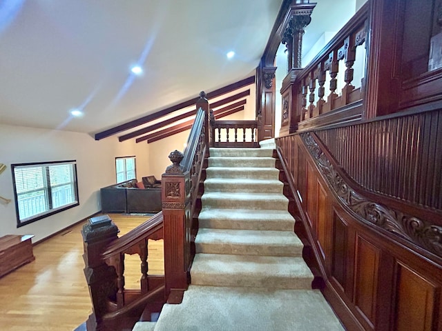 stairs featuring hardwood / wood-style floors and vaulted ceiling with beams