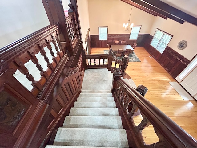 stairway featuring high vaulted ceiling, a notable chandelier, wood-type flooring, and beam ceiling