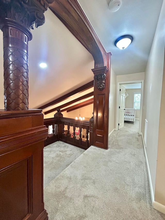 corridor featuring lofted ceiling with beams, a chandelier, and light colored carpet