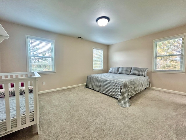 bedroom featuring light colored carpet and multiple windows