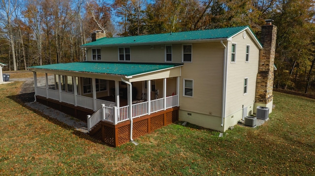 rear view of house with central air condition unit and a lawn