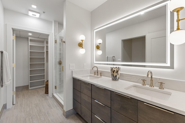 106 W Vine St Unit 407, Lexington, KY 40507 - bathroom featuring a stall shower, wood finished floors, a walk in closet, and double vanity