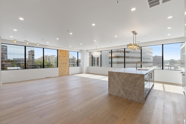 106 W Vine St Unit 407, Lexington, KY 40507 - unfurnished living room featuring light wood finished floors, a chandelier, a city view, a sink, and recessed lighting