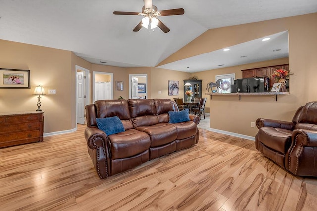 living room featuring ceiling fan, lofted ceiling, and light wood-type flooring