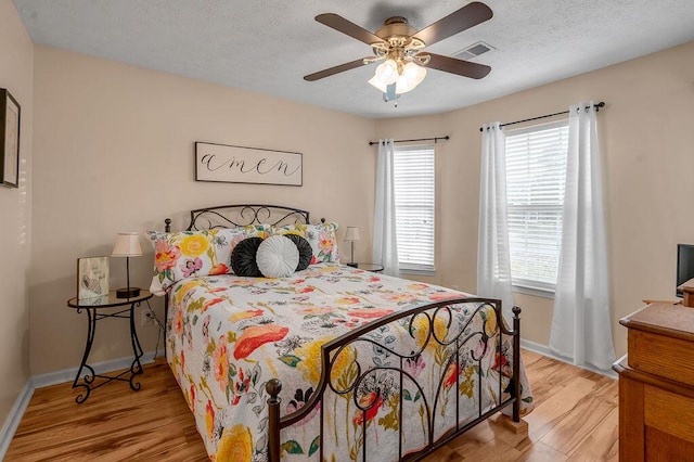 bedroom featuring ceiling fan, light hardwood / wood-style floors, and a textured ceiling