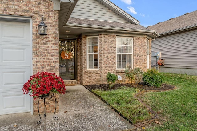 doorway to property with a garage and a yard