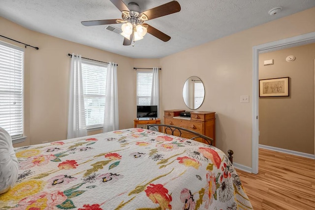 bedroom featuring ceiling fan, light hardwood / wood-style flooring, and a textured ceiling