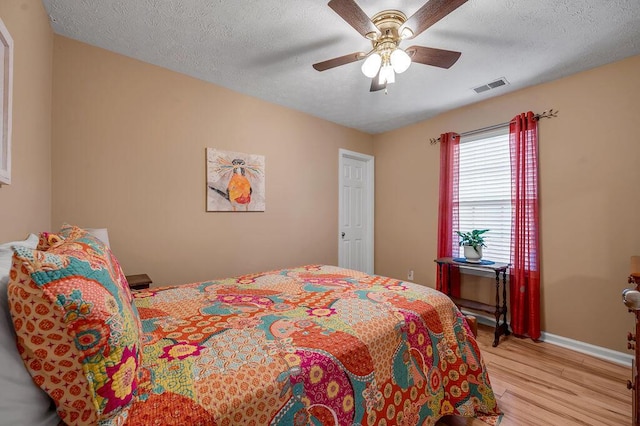 bedroom featuring ceiling fan, light hardwood / wood-style floors, and a textured ceiling