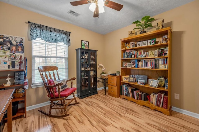 living area featuring ceiling fan, hardwood / wood-style floors, and a textured ceiling