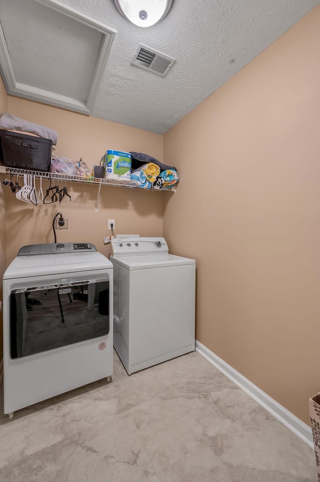 washroom with washing machine and dryer and a textured ceiling