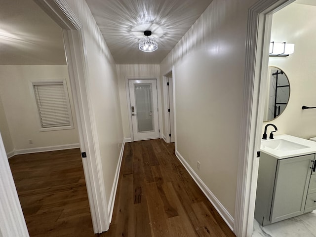 hallway featuring sink, a notable chandelier, and dark hardwood / wood-style flooring