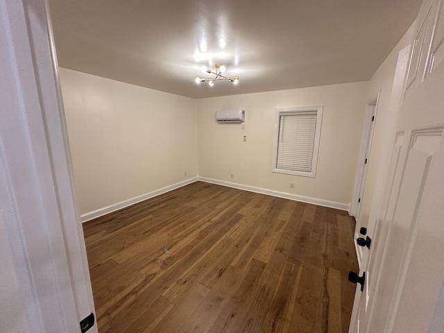 empty room with dark wood-type flooring, an AC wall unit, and an inviting chandelier