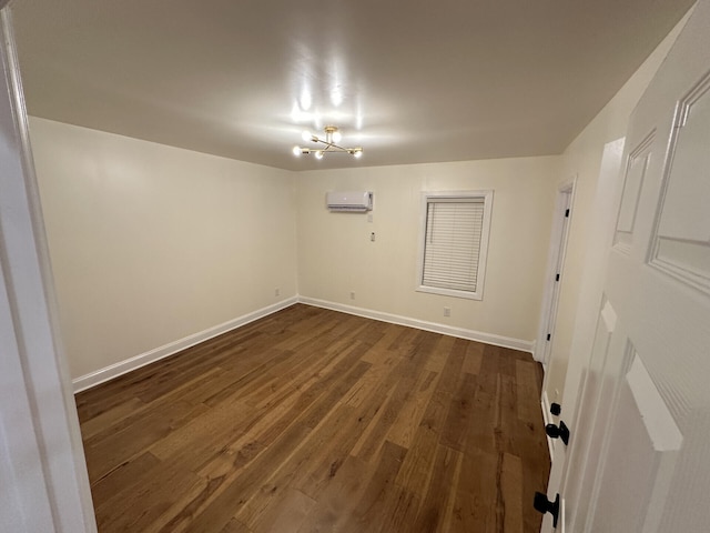 unfurnished room featuring a notable chandelier, an AC wall unit, and dark hardwood / wood-style floors