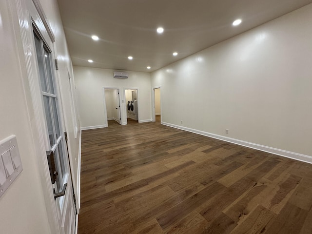 spare room featuring washer / dryer, a wall unit AC, and dark hardwood / wood-style flooring