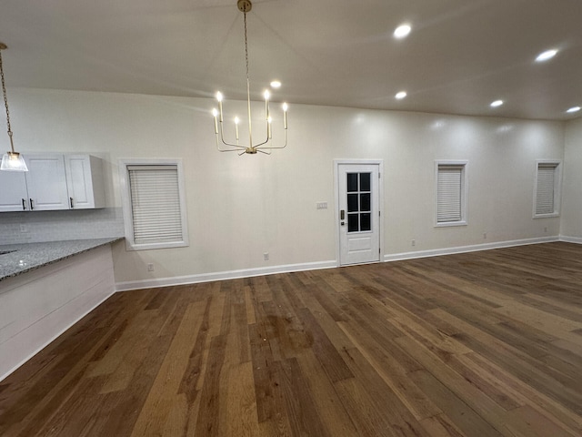 unfurnished dining area with a chandelier and dark wood-type flooring