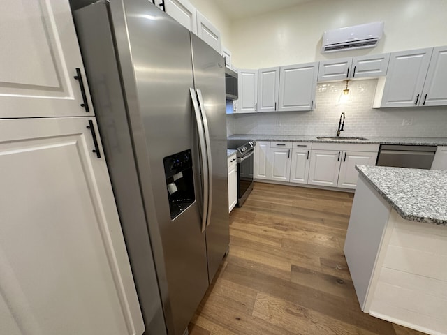 kitchen featuring light stone countertops, appliances with stainless steel finishes, sink, light hardwood / wood-style floors, and white cabinets