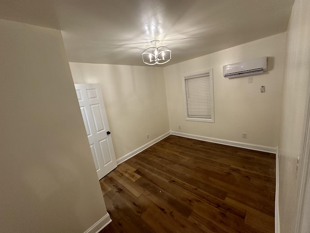 spare room featuring a notable chandelier, dark wood-type flooring, and a wall unit AC