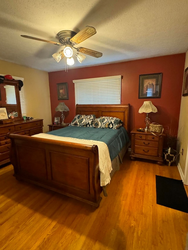 bedroom with a textured ceiling, light wood-type flooring, and ceiling fan