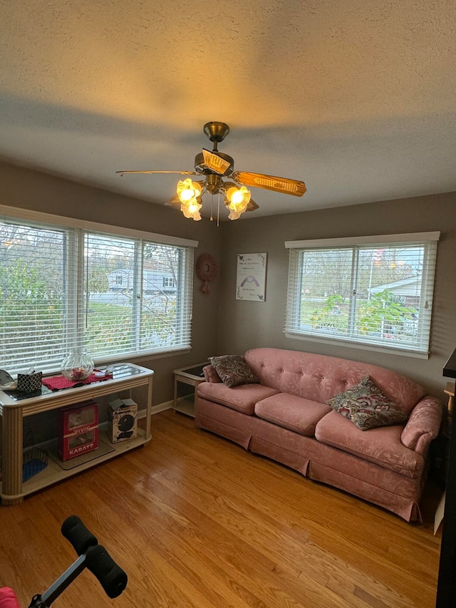 living room featuring a textured ceiling, light hardwood / wood-style floors, and ceiling fan